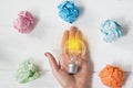 Brilliant and original idea suggested by glowing light bulb in womanÃ¢â¬â¢s hand and crumpled paper against white background
